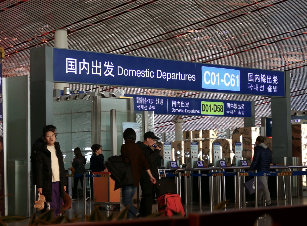 공항 국내선 출발 안내판과 여행객 국내선 출발 안내판 아래 여행객들이 이동하는 공항 내부 모습
